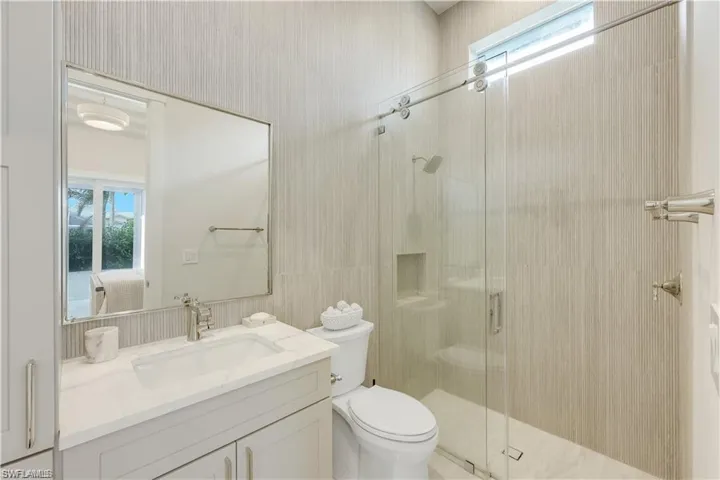 Full bathroom featuring healthy amount of natural light, vanity, a stall shower, and ensuite bathroom