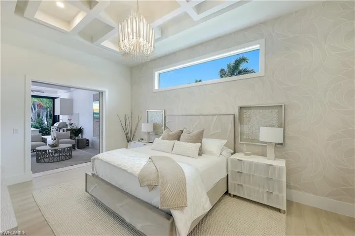 Bedroom with multiple windows, coffered ceiling, wood finished floors, and hanging lights