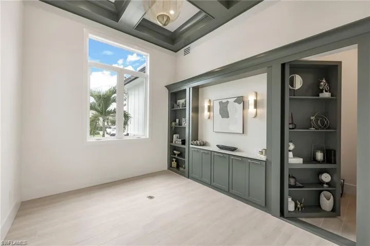 Bar featuring coffered ceiling, light wood-style floors, open shelves, and light countertops