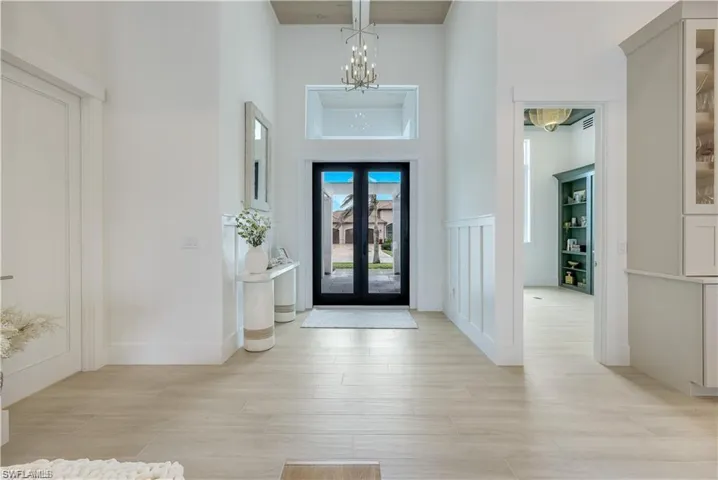 Entrance foyer featuring suspended lighting, a high ceiling, french doors, and light wood-style flooring