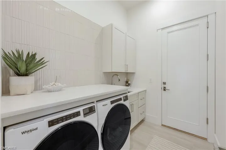 Laundry area featuring light wood-style flooring, cabinet space, and washing machine and dryer