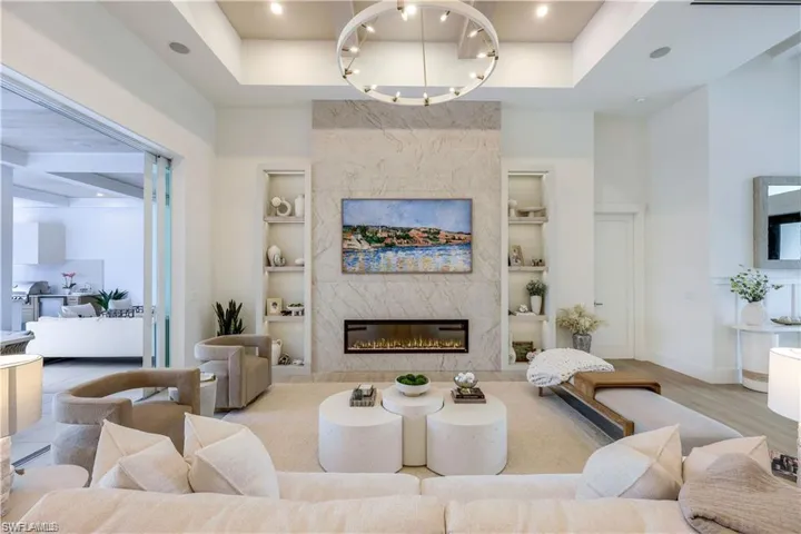 Living area featuring a high end fireplace, recessed lighting, a high ceiling, and wood finished floors