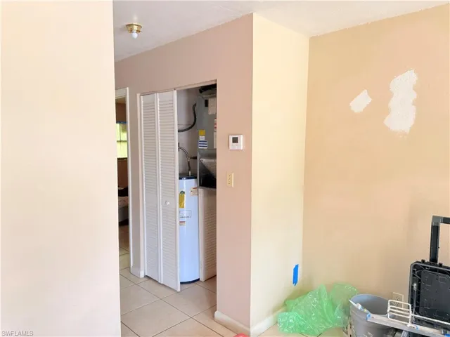 Corridor with light tile patterned floors and gas water heater