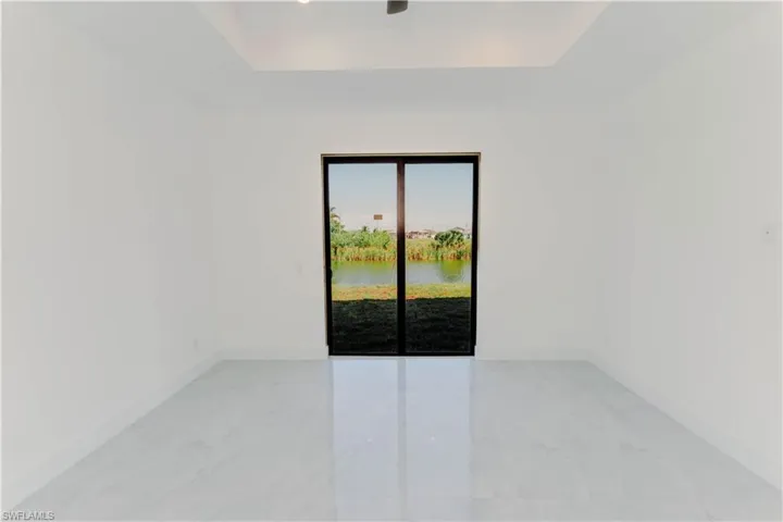 Unfurnished room with a tray ceiling, baseboards, and marble finish floor