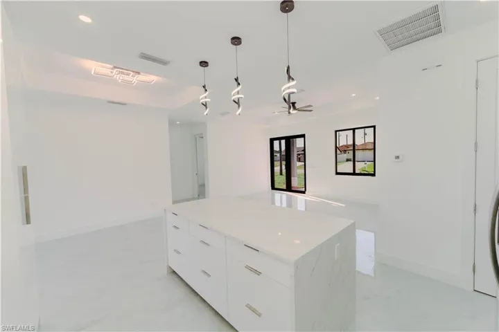 Kitchen with visible vents, a kitchen island, a tray ceiling, white cabinets, and modern cabinets