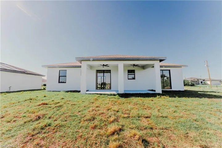 Back of property featuring a yard, a patio, ceiling fan, and stucco siding