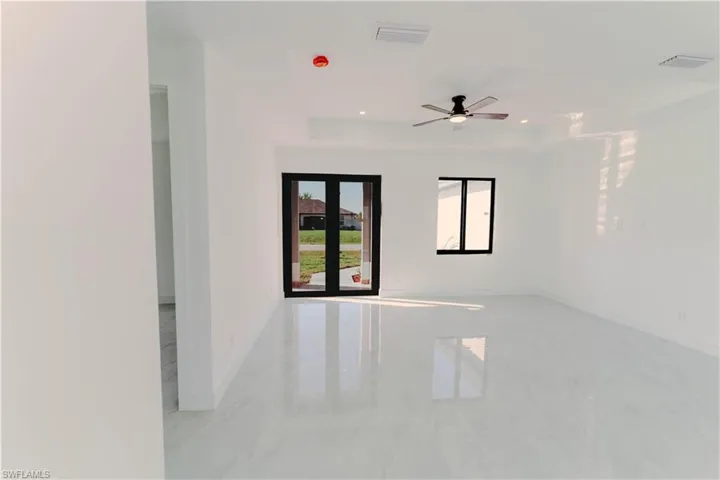 Empty room with visible vents, baseboards, a tray ceiling, marble finish floor, and a ceiling fan