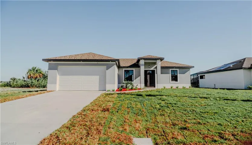 Prairie-style house with concrete driveway, an attached garage, a front lawn, and stucco siding