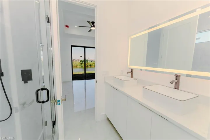 Full bath featuring marble finish floor, a stall shower, ceiling fan, and a sink