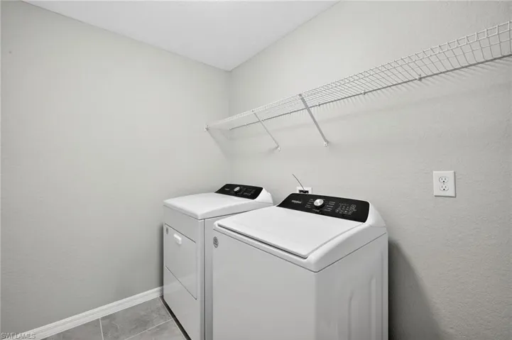 Laundry room featuring washer and clothes dryer and a textured wall