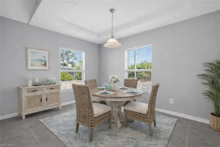 Virtually staged dining room featuring plenty of natural light, a tray ceiling, and dark tile patterned floors