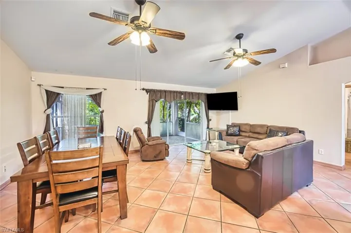 Living room featuring vaulted ceiling, light tile patterned floors, and ceiling fan