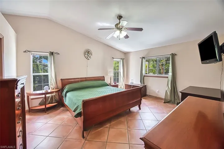 Bedroom with lofted ceiling, light tile patterned floors, and a ceiling fan