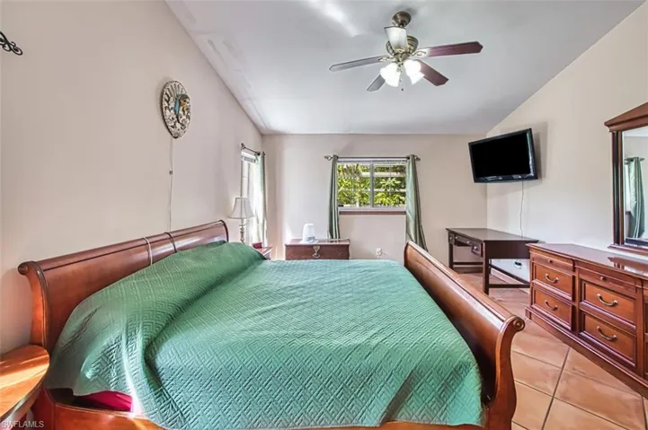 Bedroom featuring light tile patterned floors, vaulted ceiling, and a ceiling fan