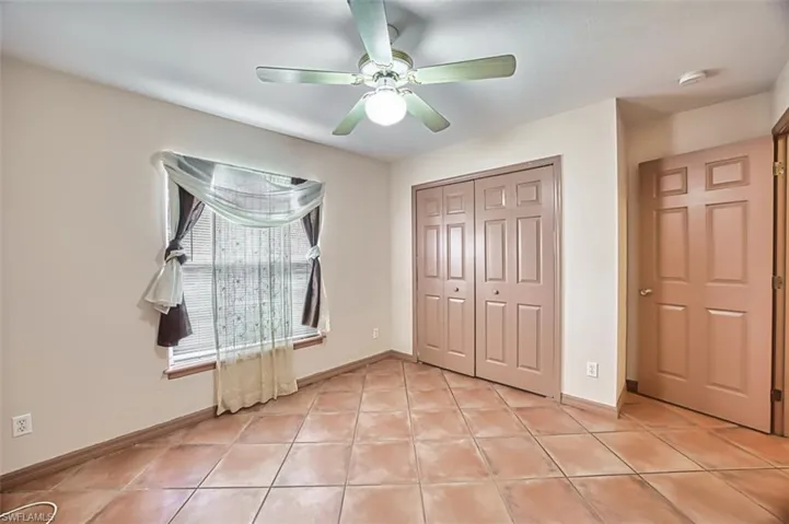 Unfurnished bedroom with light tile patterned floors, a closet, and a ceiling fan