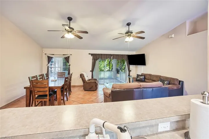 Living room featuring lofted ceiling, light tile patterned floors, and a ceiling fan
