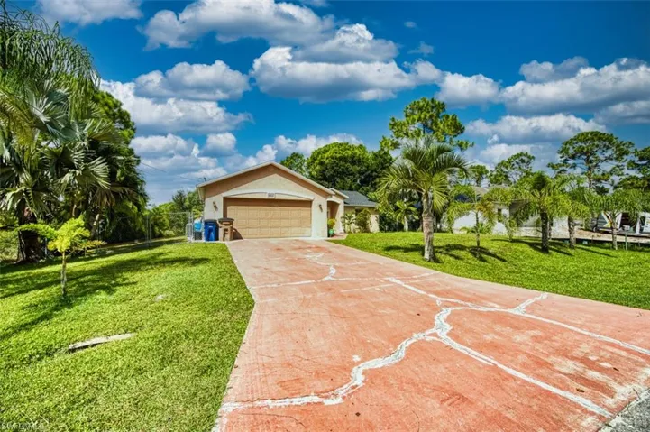 Ranch-style home with a front lawn, driveway, a garage, and stucco siding