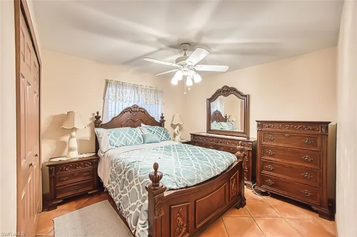 Bedroom with light tile patterned floors, a closet, and a ceiling fan