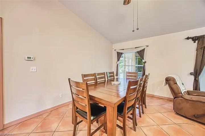 Dining space with light tile patterned flooring, lofted ceiling, and a ceiling fan