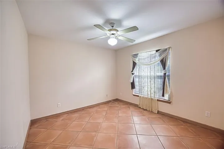 Empty room with light tile patterned floors and ceiling fan