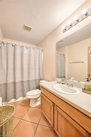 Full bathroom featuring vanity, light tile patterned floors, and a textured ceiling
