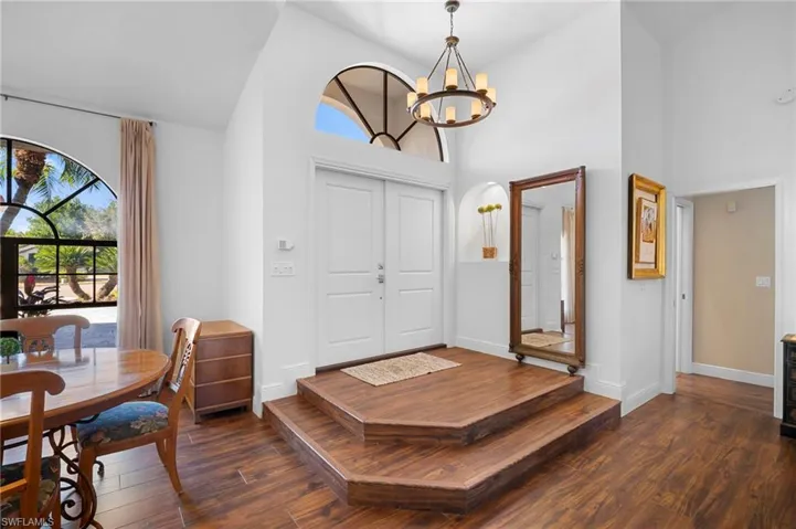 Foyer with suspended lighting, dark wood finished floors, vaulted ceiling, and healthy amount of natural light