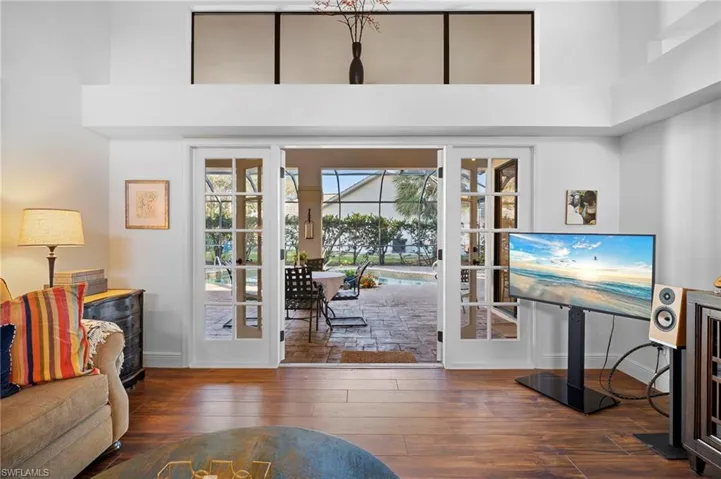 Living room with french doors, dark wood finished floors, and a high ceiling