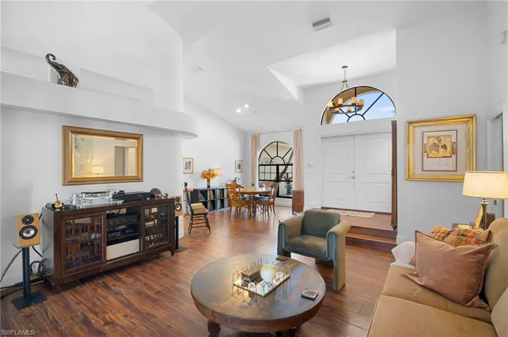 Living area with hanging lights, dark wood-style floors, and lofted ceiling