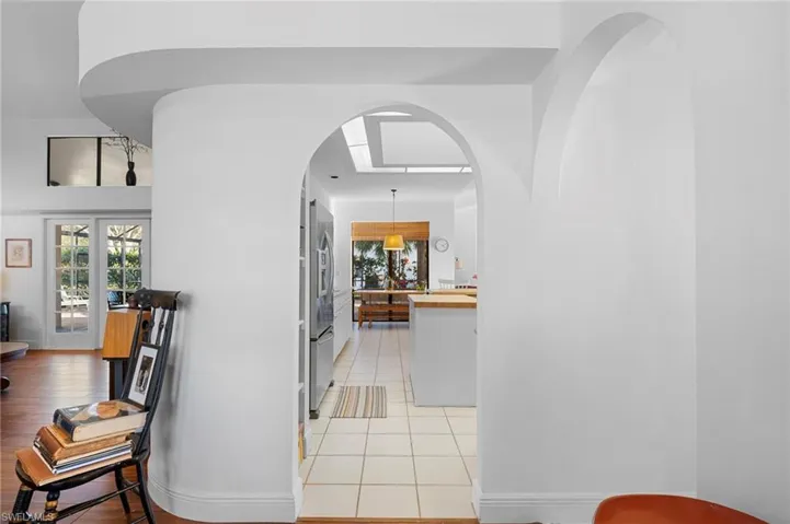 Hall featuring arched walkways and light tile patterned floors