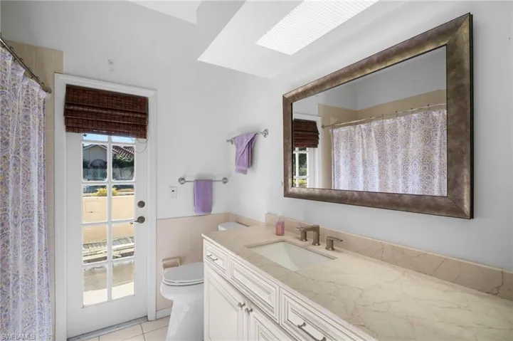 Bathroom with vanity, a shower with shower curtain, plenty of natural light, tile walls, and a wainscoted wall