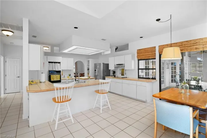 Kitchen with a breakfast bar area, white cabinets, black appliances, and decorative light fixtures