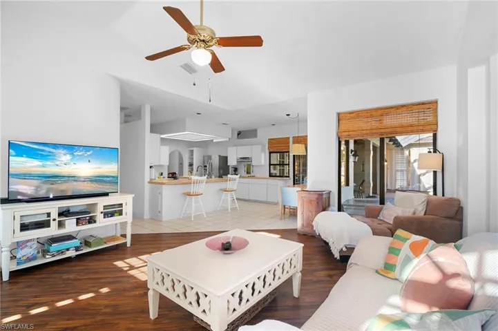 Living room featuring a ceiling fan, light wood-style floors, and vaulted ceiling