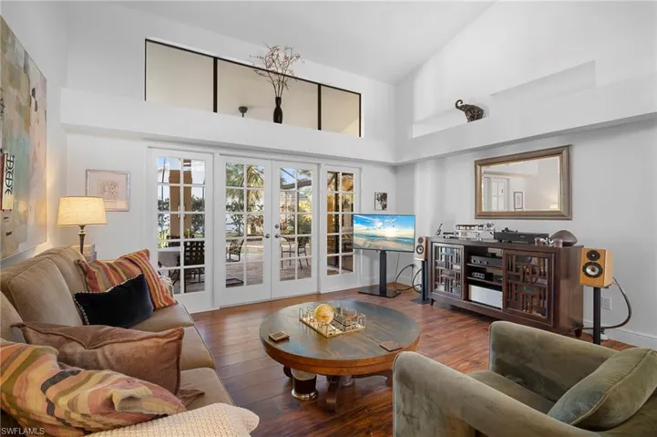 Living area with french doors, wood-type flooring, and lofted ceiling