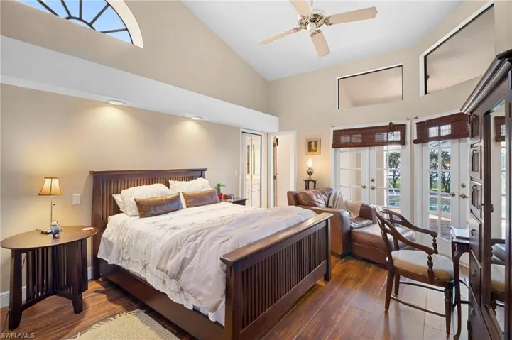 Bedroom with wood finished floors, french doors, access to exterior, lofted ceiling, and ceiling fan