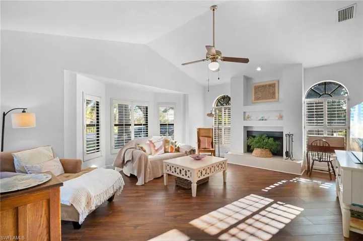 Living area featuring dark wood-style floors, ceiling fan, lofted ceiling, and a tile fireplace