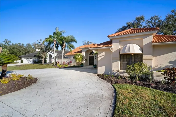 Mediterranean / spanish house with stucco siding, a tile roof, and curved driveway