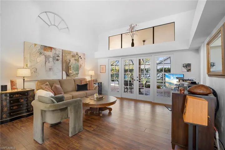 Living room with french doors, wood finished floors, and a high ceiling