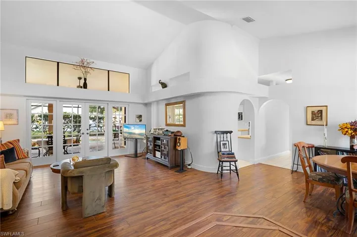 Living room featuring french doors, vaulted ceiling, arched walkways, and hardwood / wood-style flooring