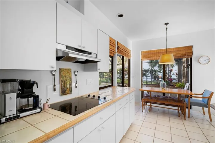 Kitchen with white cabinetry, hanging light fixtures, black electric cooktop, tile countertops, and light tile patterned floors