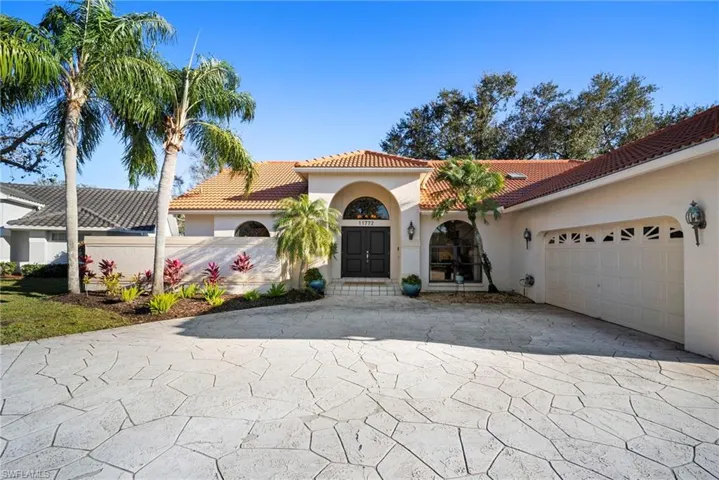 Mediterranean / spanish house with a tile roof, driveway, stucco siding, and an attached garage