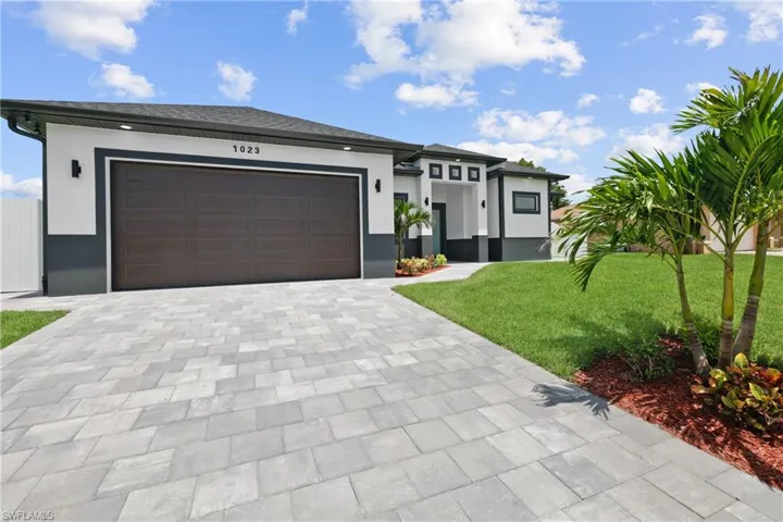 View of front of property featuring a garage and a front lawn