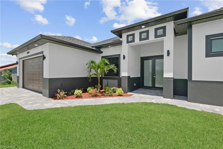 Contemporary house featuring a garage, a front lawn, and french doors