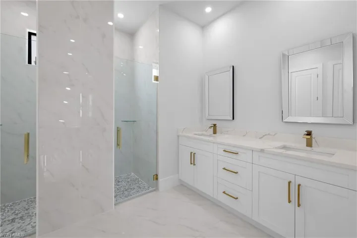 Bathroom featuring tile patterned flooring, an enclosed shower, and double vanity
