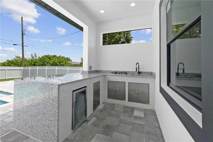 View of patio with sink, a fenced in pool, and an outdoor kitchen