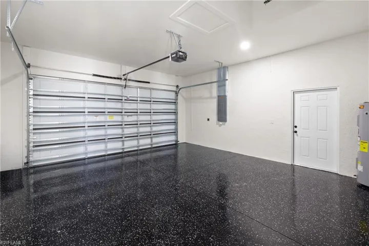 Garage featuring a garage door opener, electric water heater, and electric panel