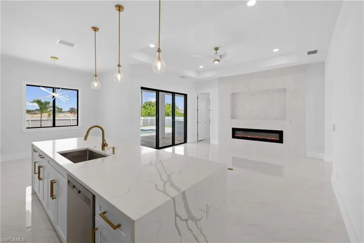 Kitchen with sink, a tray ceiling, light stone counters, dishwasher, and ceiling fan