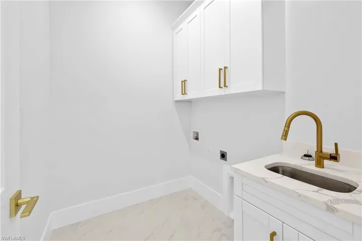 Laundry area featuring electric dryer hookup, washer hookup, cabinets, light tile patterned floors, and sink