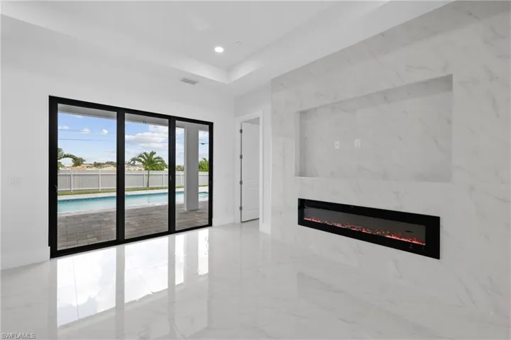 Empty room featuring a raised ceiling, a high end fireplace, and light tile patterned floors