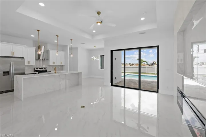 Kitchen featuring a raised ceiling, light tile patterned floors, and stainless steel refrigerator with ice dispenser