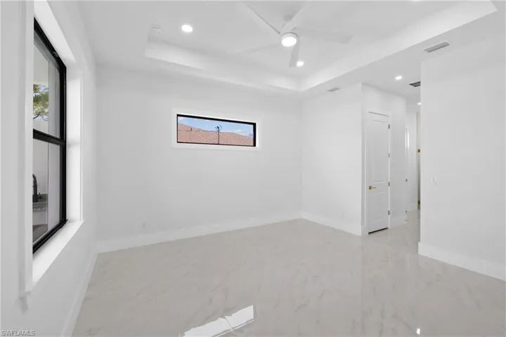 Spare room with ceiling fan, light tile patterned floors, and a tray ceiling